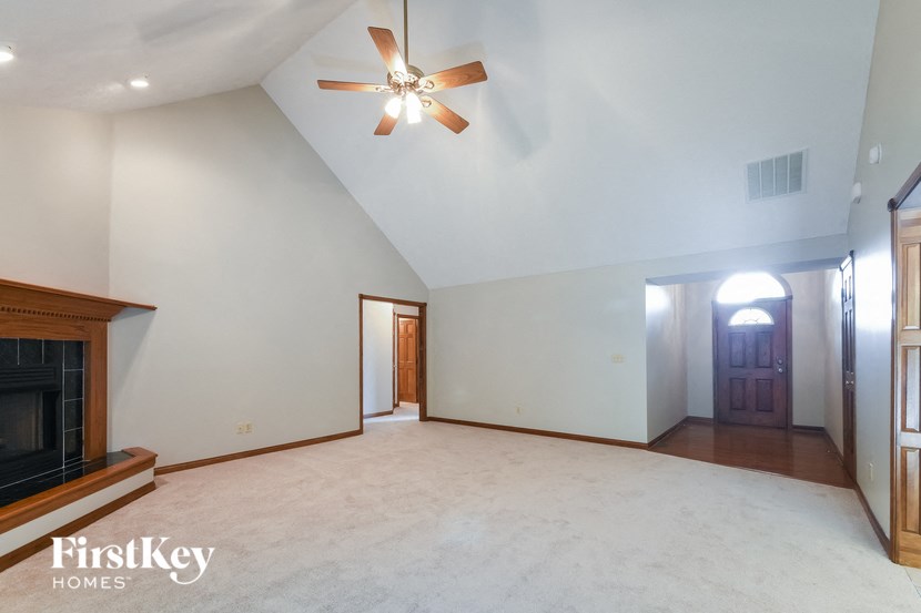 an empty living room with a fireplace and a ceiling fan