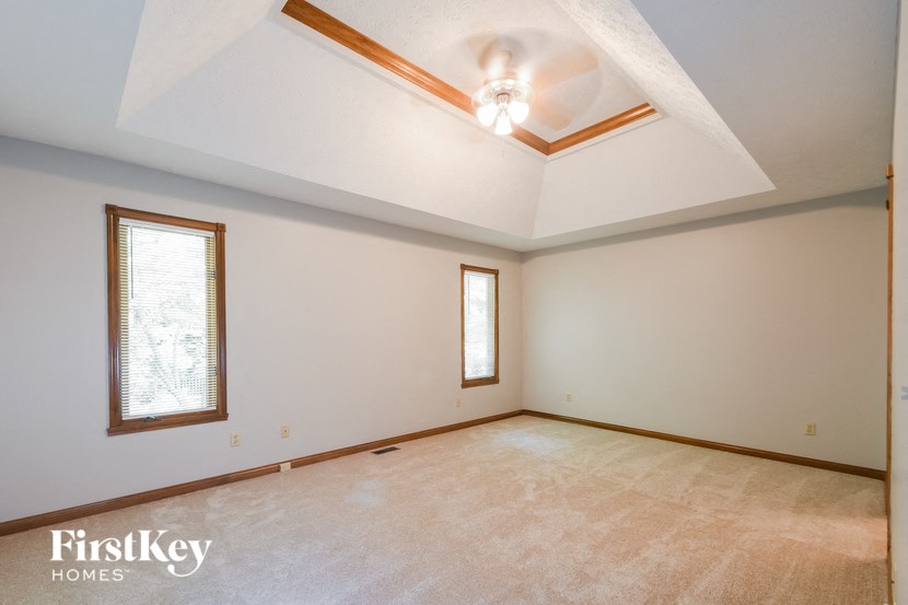 an empty living room with a ceiling fan and two windows