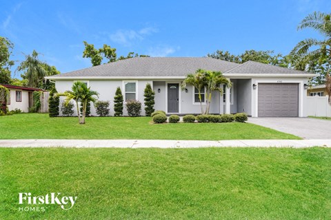 A house with a grey roof and a white garage door is for sale.