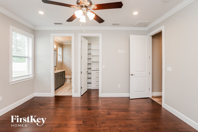 A room with a ceiling fan and wooden floors.