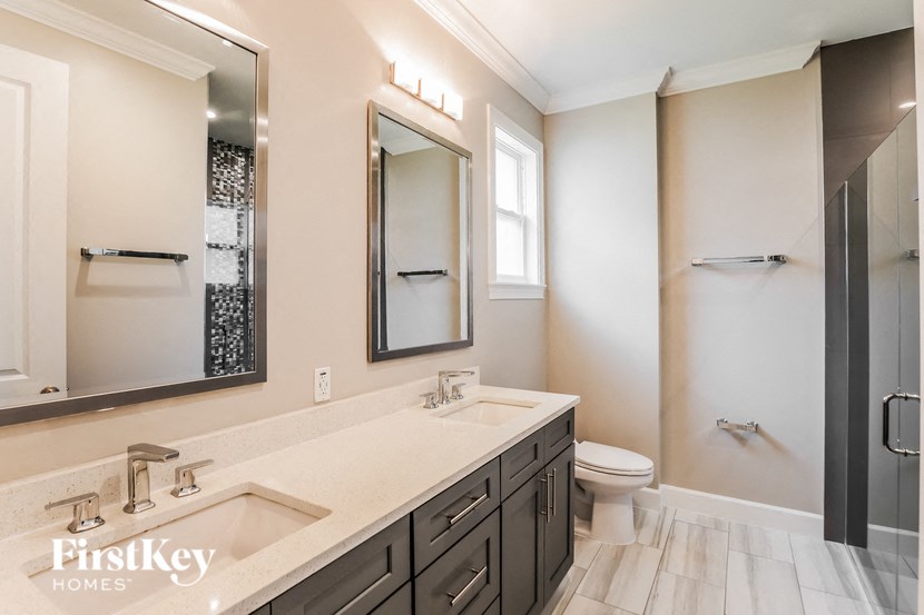 A bathroom with a sink, mirror, toilet and shower.