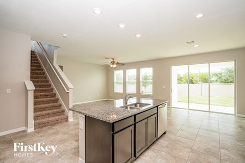 A kitchen with granite countertops and stainless steel appliances is shown in a model home.