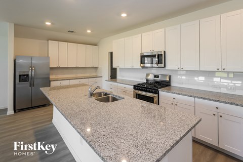 a large kitchen with white cabinets and granite counter tops