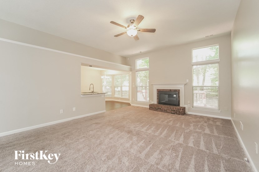 an empty living room with a ceiling fan and a fireplace