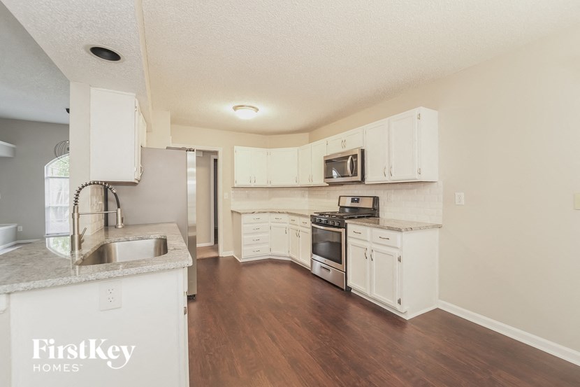 an empty kitchen with white cabinets and stainless steel appliances