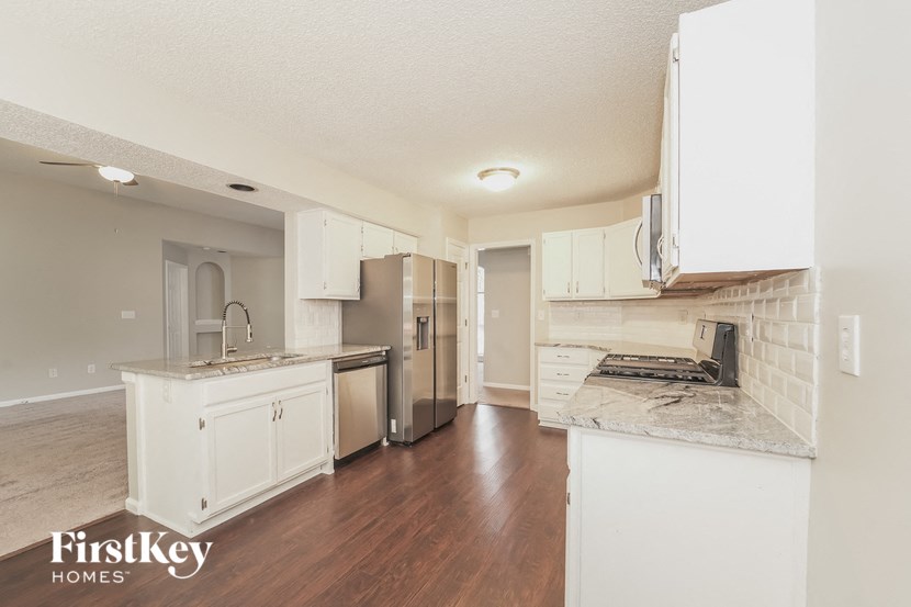 a kitchen with white cabinets and a stainless steel refrigerator