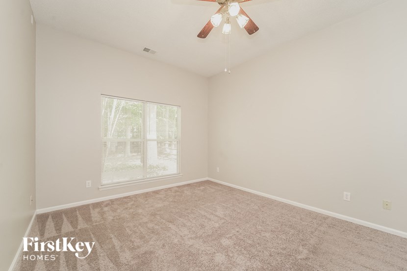 an empty living room with a ceiling fan and a window