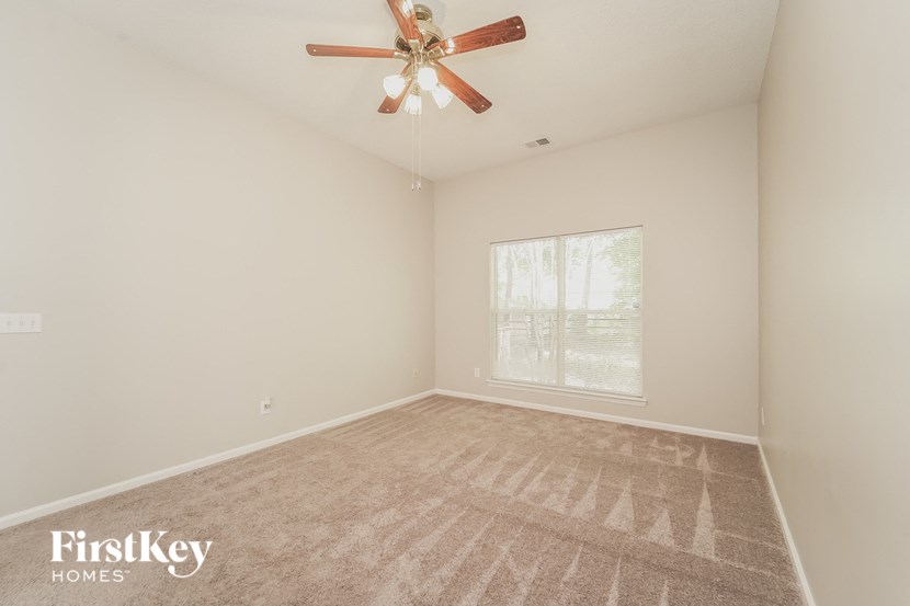 an empty living room with a ceiling fan and a window