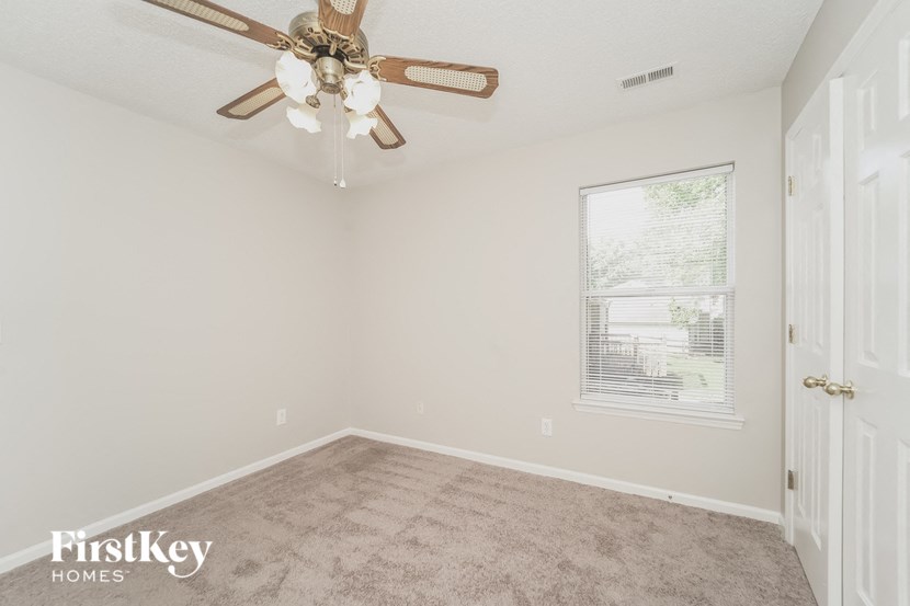 an empty bedroom with a ceiling fan and a window