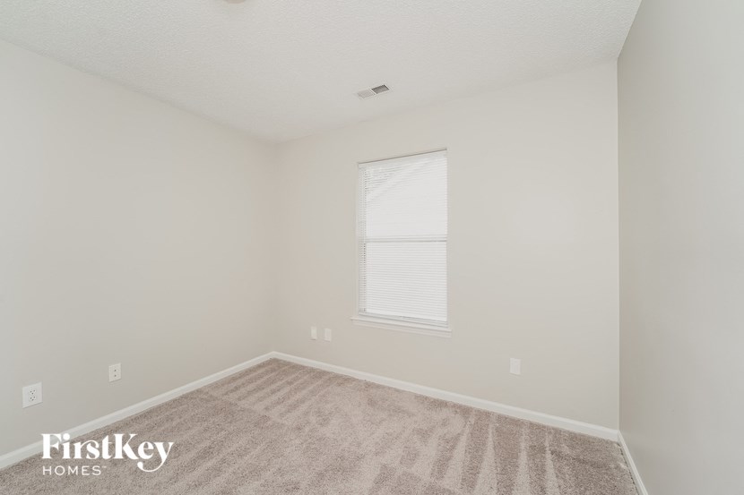the bedroom of a home with a large window and carpet