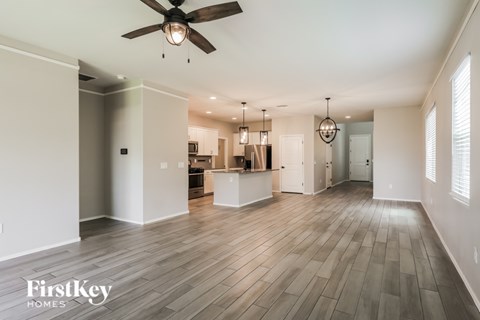A spacious room with a ceiling fan and pendant lights.