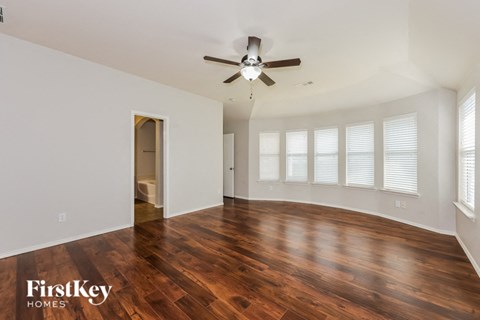 A spacious room with wooden floors and a ceiling fan.