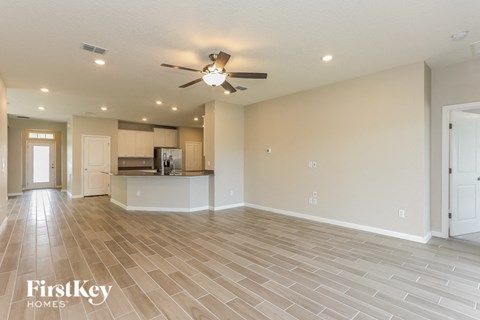 A spacious living room with a ceiling fan and lighting fixtures.