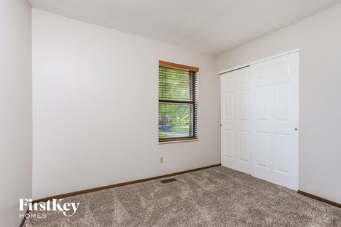the living room of a home with white walls and carpet and a window