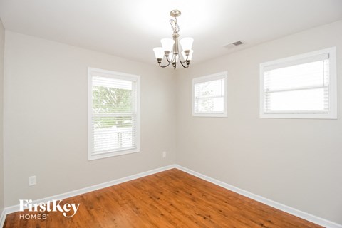 a empty dining room with a wood floor and a chandelier