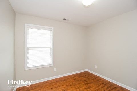 a bedroom with a hardwood floor and a window