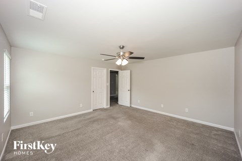 a spacious living room with carpet and a ceiling fan