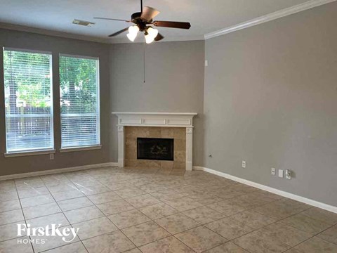 an empty living room with a fireplace and a ceiling fan