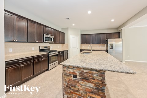 A kitchen with a stone counter and wooden cabinets.