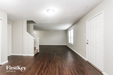 A spacious room with wooden floors and white walls.