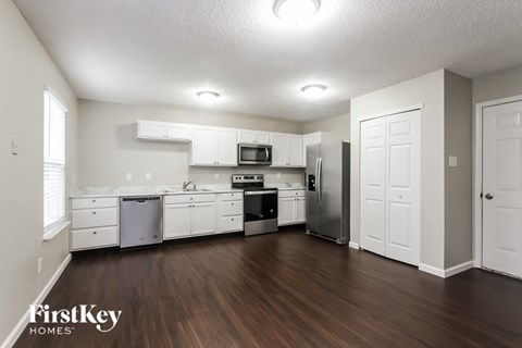 A kitchen with white cabinets and a wooden floor.