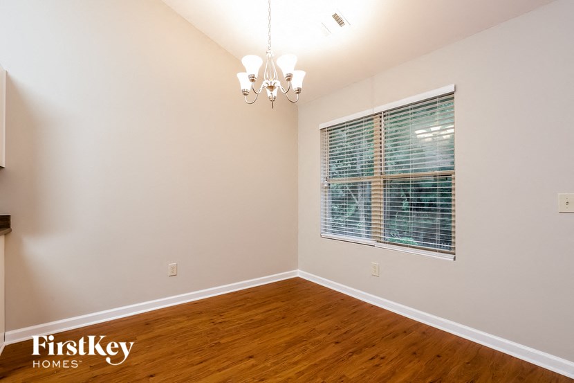 a bedroom with a large window and wood flooring and a chandelier