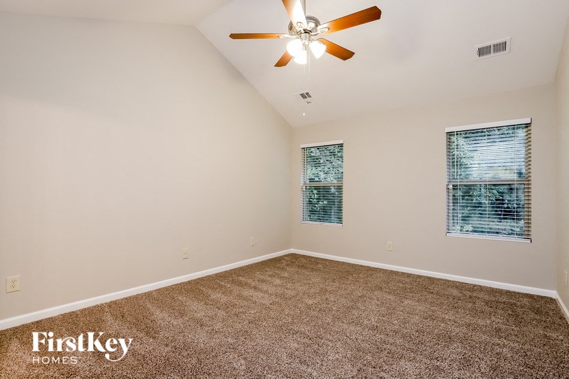 the master bedroom has a carpeted floor and a ceiling fan