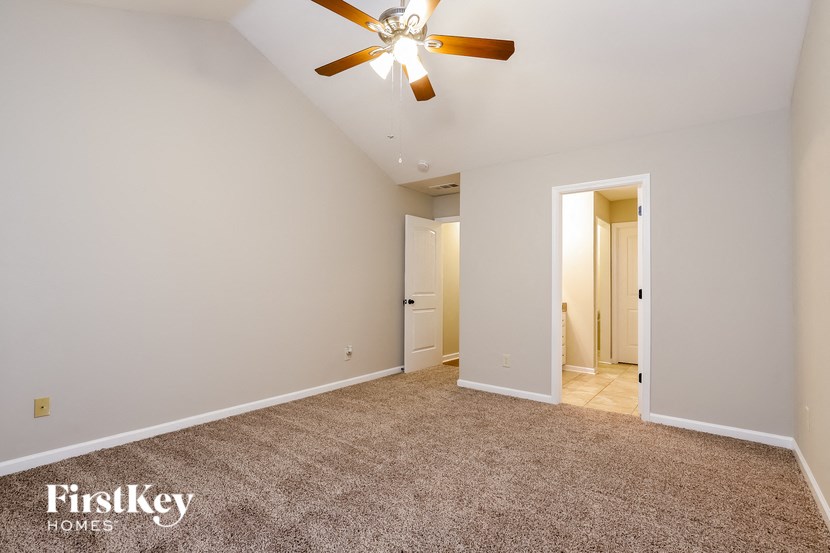 a spacious living room with carpet and a ceiling fan