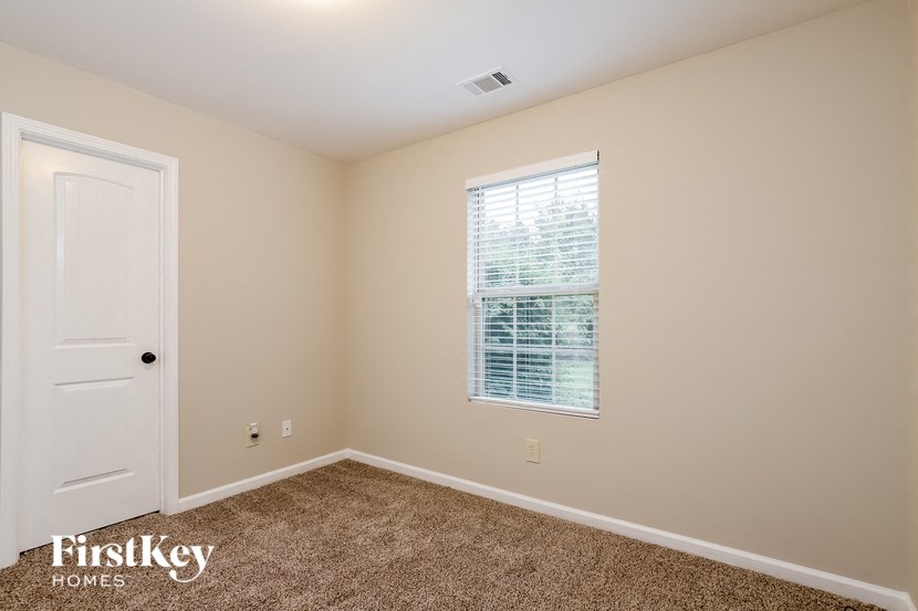 a bedroom with carpet and a window and a door