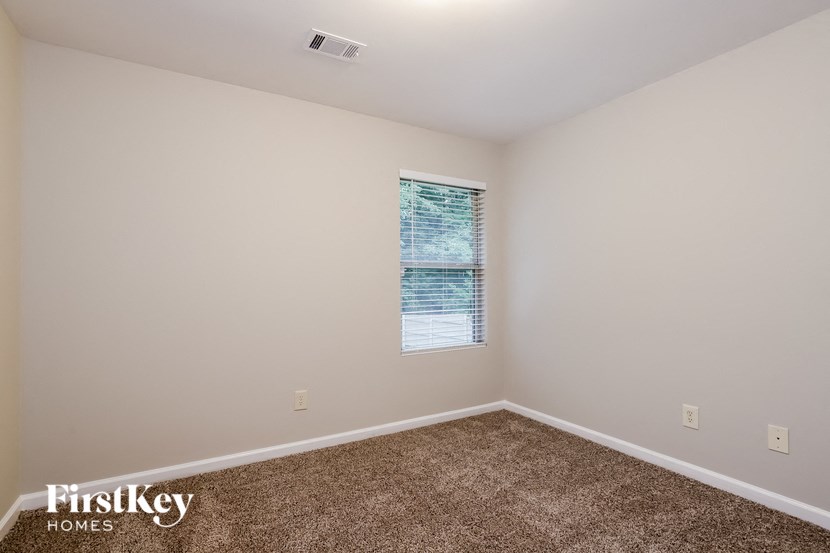 the bedroom has carpeted floors and a large window