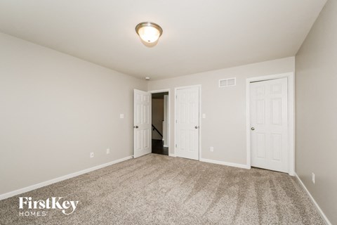 a spacious living room with carpet and white doors