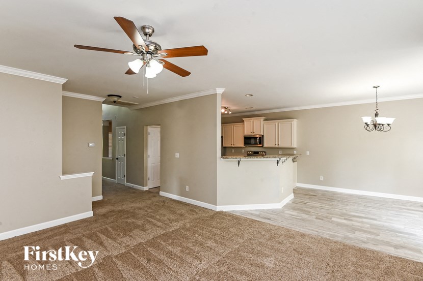 an empty living room and kitchen with a ceiling fan