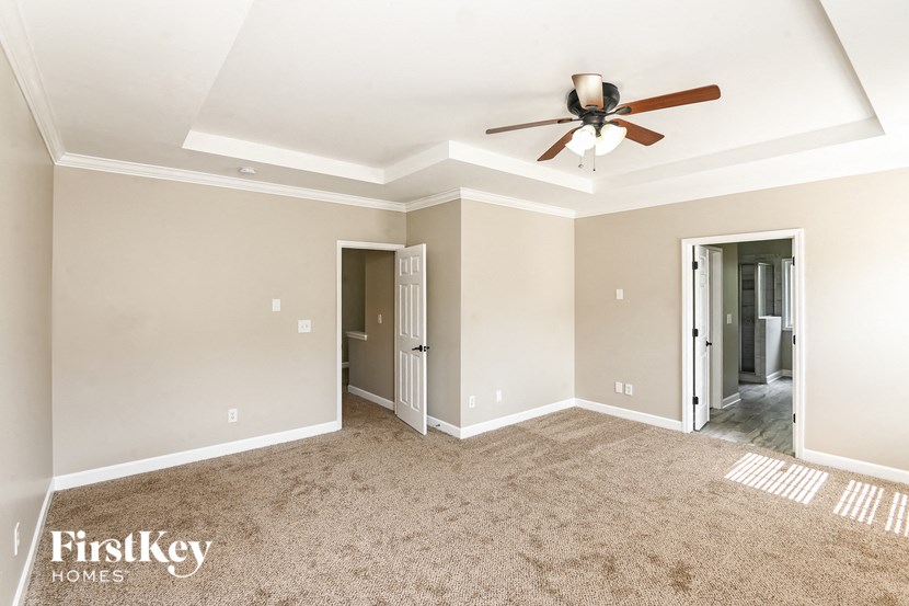 a empty living room with a ceiling fan and carpet