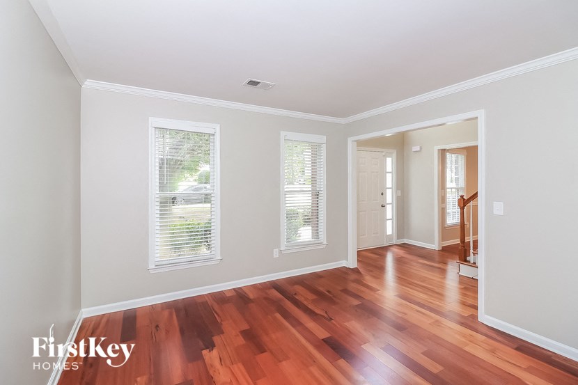 a renovated living room with wood floors and white walls and a door to a hallway