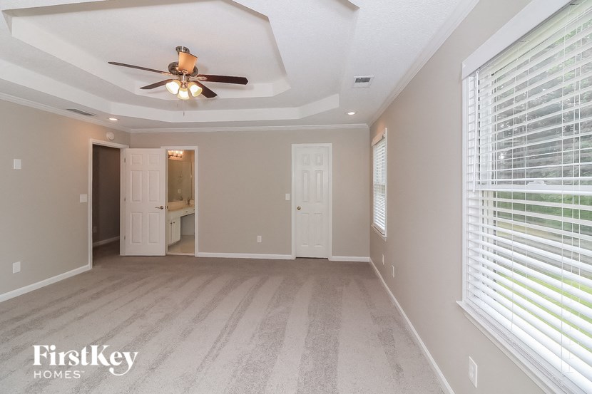an empty living room with a ceiling fan and a large window