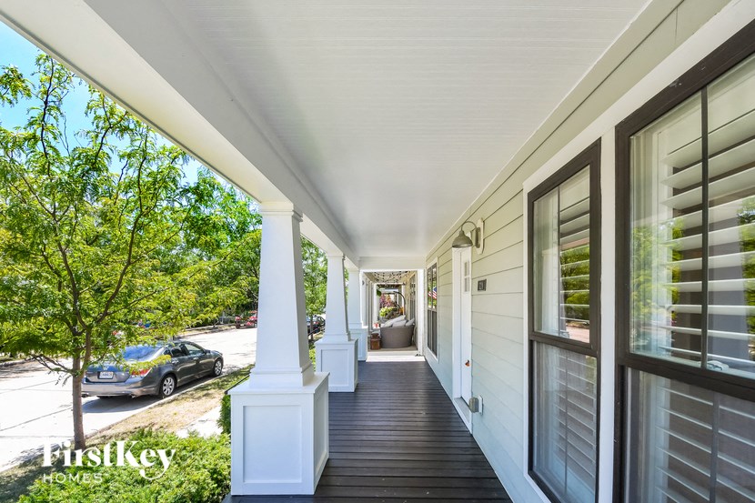 the front porch of a home with windows and a car parked on the street