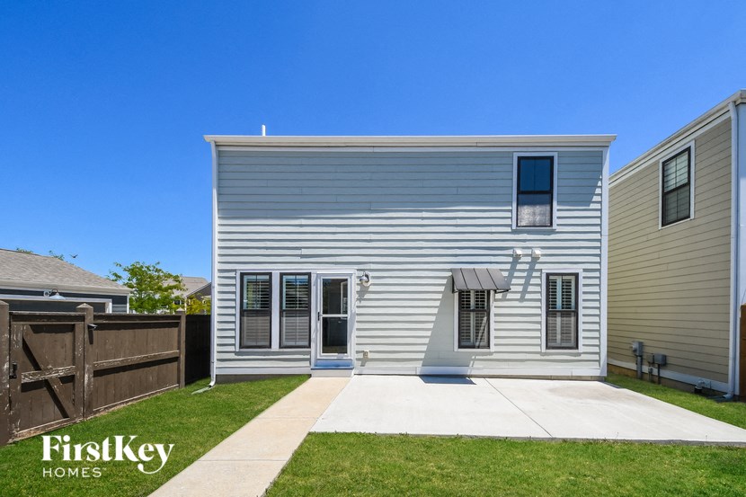 a small white house with a yard and a wooden fence