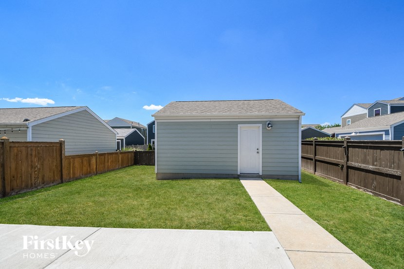 a small shed in the backyard of a house with a lawn