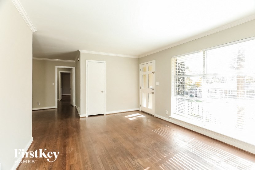 A spacious room with wooden floors and white walls.