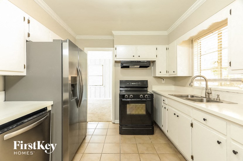 A kitchen with a refrigerator, oven, and sink.