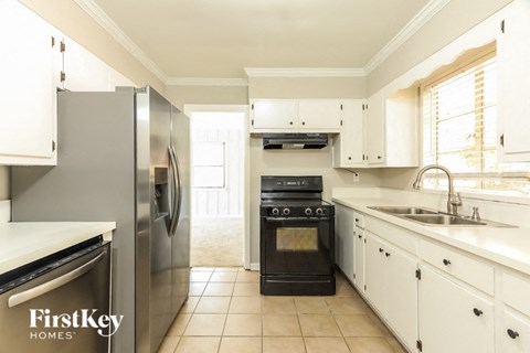 A kitchen with a refrigerator, oven, and sink.