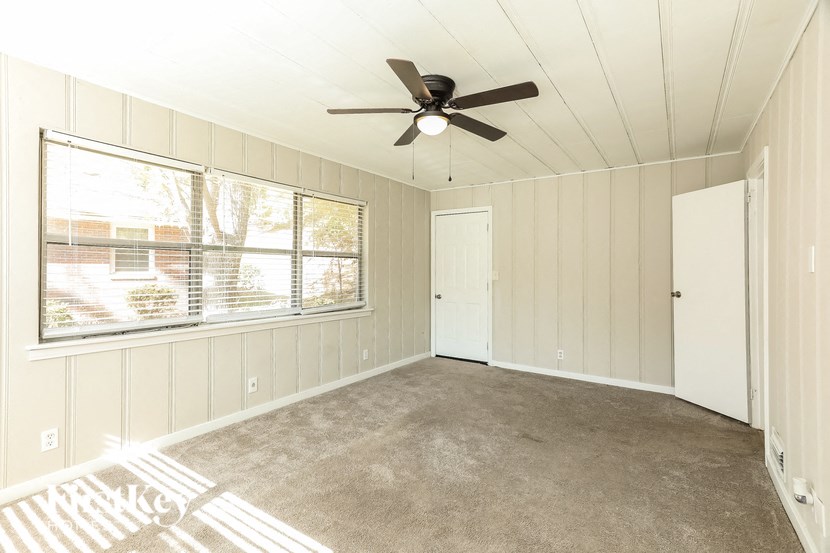 A room with a ceiling fan and a window with blinds.