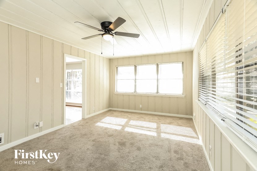 A spacious room with a ceiling fan and large windows.