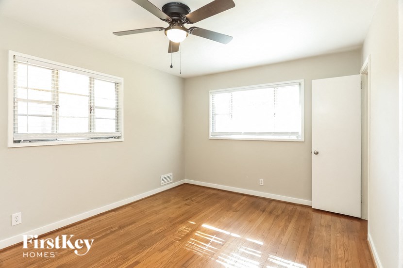 A room with a ceiling fan and two windows.