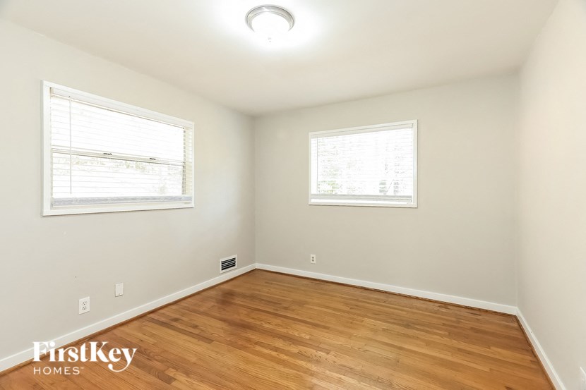 A room with wooden floors and two windows.