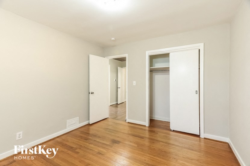 A room with wooden floors and white walls, with a door on the left and another door on the right.
