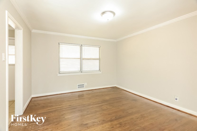A room with wooden floors and a window with blinds.