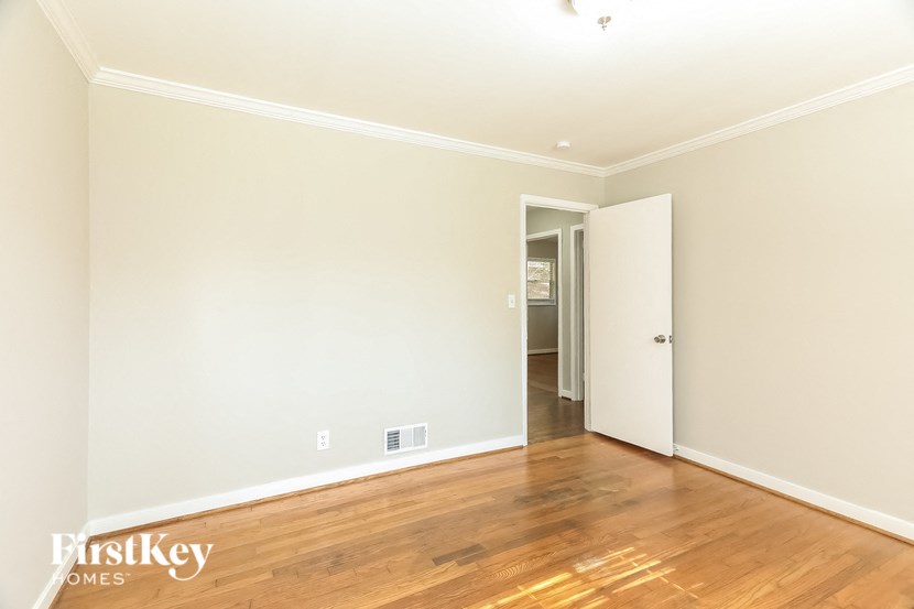 A room with wooden floors and a doorway leading to another room.
