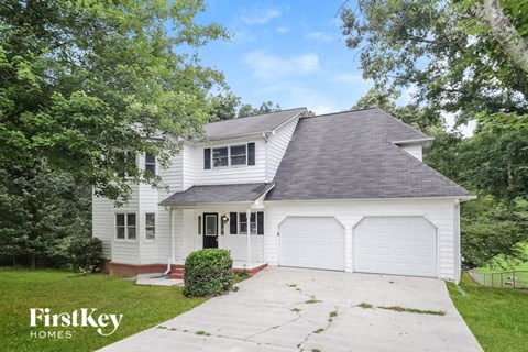 a white house with a gray roof and a driveway