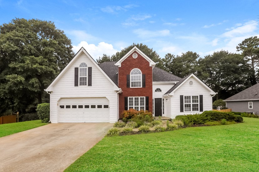 A white house with a red brick chimney and a brown garage door.